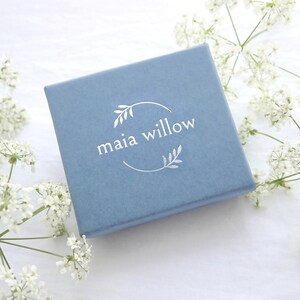 May include: A light blue gift box with a silver foil logo that reads "maia willow" in a circle with a leafy design.