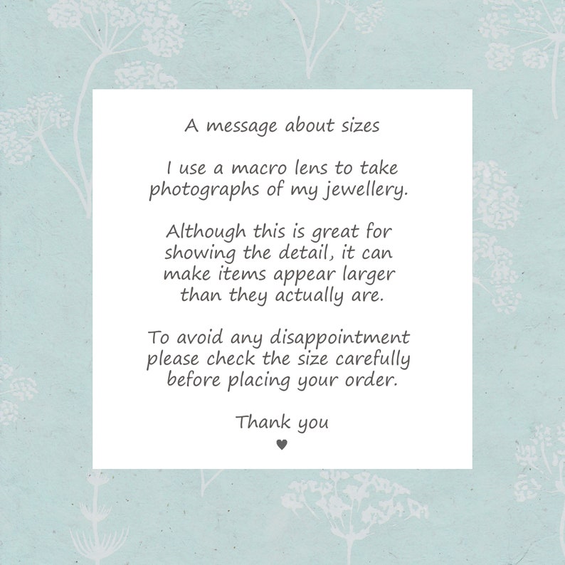 May include: A message about sizes in a white rectangle on a light blue background with white floral designs. The message explains that macro lenses are used to take photos of jewelry, which can make items appear larger than they actually are. The message encourages buyers to check the size carefully before placing an order. The message ends with "Thank you".