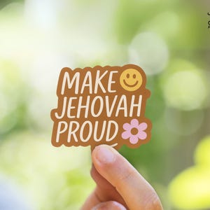 May include: Brown sticker with the text "Make Jehovah Proud" in white lettering. A yellow smiley face and a pink flower are also on the sticker.