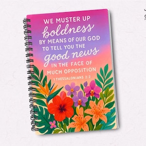 May include: A spiral-bound notebook with a vibrant floral design and the text "WE MUSTER UP boldness...good news." The cover has a pink, purple, and orange gradient background, with flowers and green leaves. The notebook is from JW Printables.