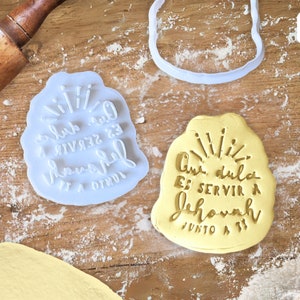 May include: Two cookie cutters, one white and one yellow, with the text "Que dulce es servir a Jehova junto a ti" in a handwritten style.