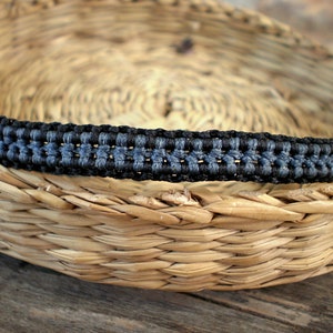 Può includere: Un braccialetto intrecciato in corda nera e blu con un motivo a trama.