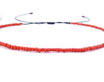 May include: A simple red beaded necklace with a black cord.