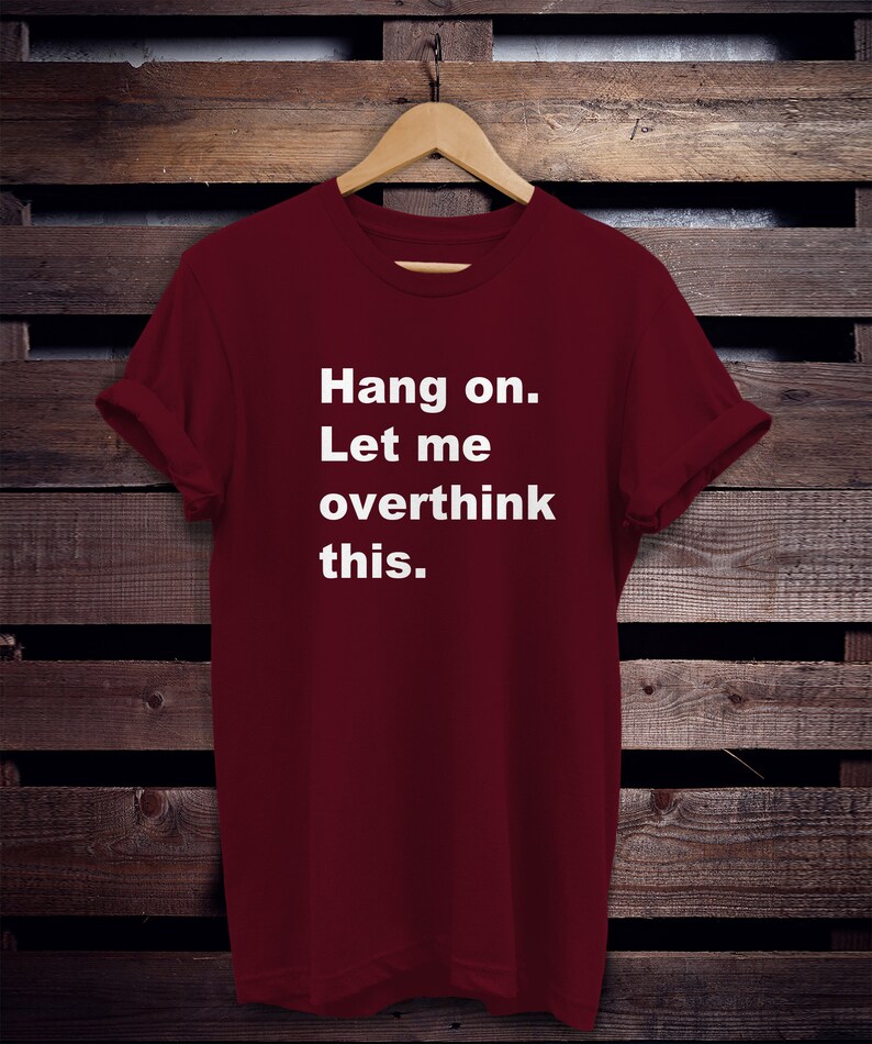 May include: A maroon t-shirt with white text that reads "Hang on. Let me overthink this."