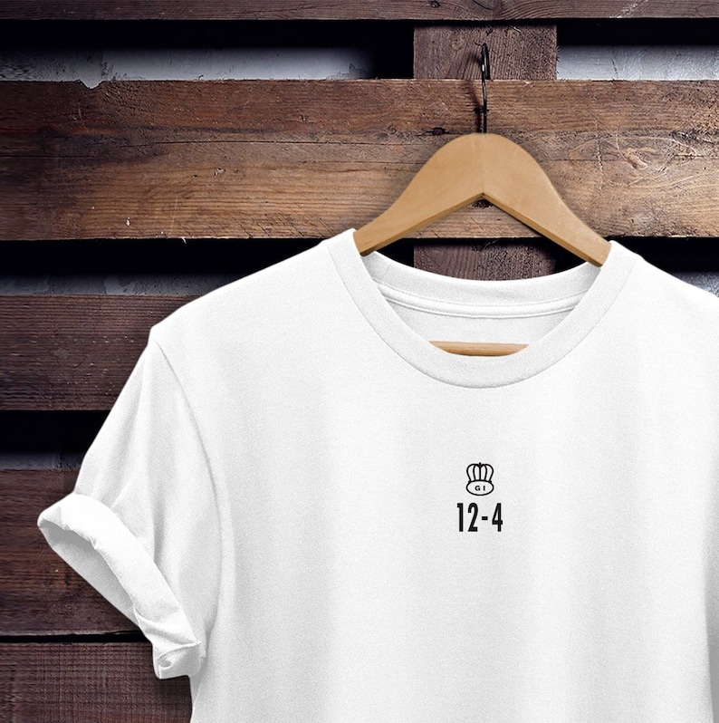 May include: White t-shirt with a black crown and the text "12-4" printed on the front.