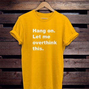 May include: Yellow t-shirt with the text "Hang on. Let me overthink this." printed in white.