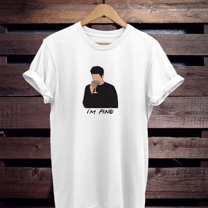 May include: White t-shirt with a black and white illustration of a person holding a glass of wine. The text "I'M FINE" is printed below the illustration.
