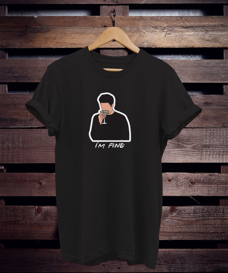 May include: Black t-shirt with a white outline of a cartoon man holding a glass of wine. The text "I'M FINE" is printed below the image.