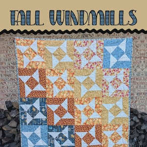 Może przedstawiać: Ręcznie robiona kołdra z patchworkowym wzorem. Kołdra posiada kwadraty w niebieskie, pomarańczowe, żółte i kwiatowe wzory. Tekst "Tall Windmills" znajduje się na górze, a "Sewl Sister for Villa Rosa Designs" na dole.