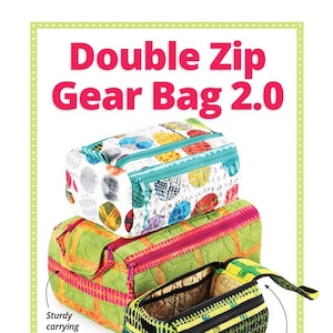 May include: Three colorful zippered bags with a double-zip flap for easy access. The bags are made of fabric with different patterns and have a sturdy carrying handle. The text "Double Zip Gear Bag 2.0" is at the top of the image. The text "Includes coupon for $5 Add-On Video Tutorial" is in a circle below the bags. The text "byannie.com ... what's in your bag?" is at the bottom of the image.