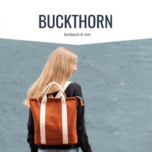 Może przedstawiać: Kobieta nosi brązowy plecak z płótna i brązową torbę z płótna z białymi paskami. Torby są oznaczone "BUCKTHORN backpack & tote" i "noodlehead".