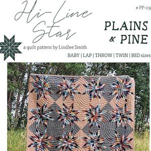 May include: A quilt pattern called "Hi-Line Star" by Lindlee Smith. The quilt is made in a patchwork style with a variety of colors and patterns. The quilt is displayed outdoors in a natural setting.