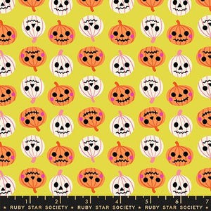 Puede incluir: Un patrón de tela con una cuadrícula repetitiva de calabazas de Halloween naranjas y blancas con rasgos faciales negros y mejillas rosadas sobre un fondo verde chartreuse, con una regla negra en la parte inferior marcada como Ruby Star Society en centímetros.