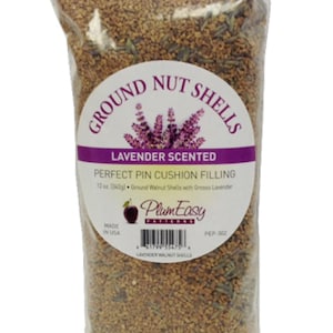 May include: A clear plastic bag filled with ground walnut shells and lavender. The bag has a label that reads "Ground Nut Shells Lavender Scented Perfect Pin Cushion Filling 12 oz (340g) Ground Walnut Shells with Grosso Lavender PlumEasy Patterns PEP-302 Lavender Walnut Shells Made in USA".