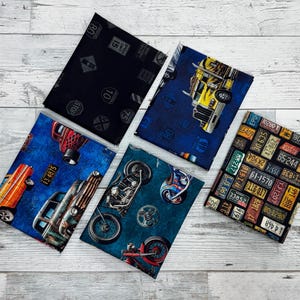 May include: Five fabric squares with different designs featuring vintage cars, motorcycles, and road signs. The squares are blue, teal, black, and brown with yellow, red, and white accents.