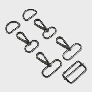 May include: A collection of black metal hardware components, including D-rings, swivel clasps, and a rectangular slider buckle. The hardware is arranged on a light gray background, suitable for bag making or other craft projects.