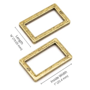 May include: Two antique brass-colored rectangular metal rings. The length is 3/4 inch (19.05 mm), and the inside width is 1 inch (25.4 mm). Each ring has a textured surface and a small logo. Ideal for crafting and hardware.