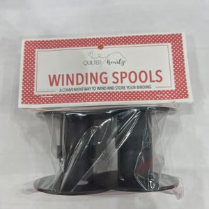 May include: Two black winding spools packaged in clear plastic. The packaging features a red and white polka dot border with the text "Quilted Heartz" and "Winding Spools" in red. The text below reads "A convenient way to wind and store your binding."