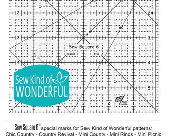 May include: Sew Square 6 ruler with markings for quilting and sewing. The ruler is made of clear acrylic and has a teal Sew Kind of Wonderful logo. The ruler is marked with inches and has a 60 degree angle.
