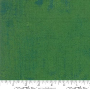 Pode incluir: Tecido verde com uma aparência texturizada e manchada. O tecido tem uma base verde escuro com detalhes em verde e verde-azulado mais claros. Uma régua está na parte inferior da imagem, com a palavra "moda" e um endereço web.