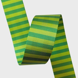 May include: A close-up of a green and yellow striped ribbon. The ribbon is a vibrant green with horizontal stripes of a lighter yellow-green. The ribbon is curled, showing both sides of the fabric.
