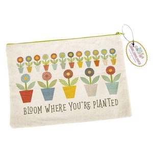 May include: A white canvas zipper pouch with a green zipper and a colorful floral design. The pouch has the text "Bloom Where You're Planted" printed on the front. The pouch has a tag attached that says "Bee & Gingham's Canvas Zipper Pouch".