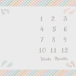 May include: A light gray baby milestone blanket with a pastel plaid border. The blanket features numbers 1-12, the words "Weeks Months", and baby footprints. The background is dotted.