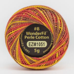 Könnte beinhalten: Ein Knäuel WonderFil Perle Cotton-Garn in Gelb-, Orange- und Brauntönen. Das Etikett lautet "#8 WonderFil Perle Cotton" und "EZM1051". Das Knäuel wiegt 5g.