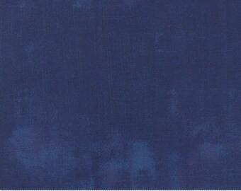 May include: Close-up of navy blue fabric with a textured, mottled appearance. The fabric has subtle colour variations, with lighter blue patches and darker blue streaks. A ruler is at the bottom.