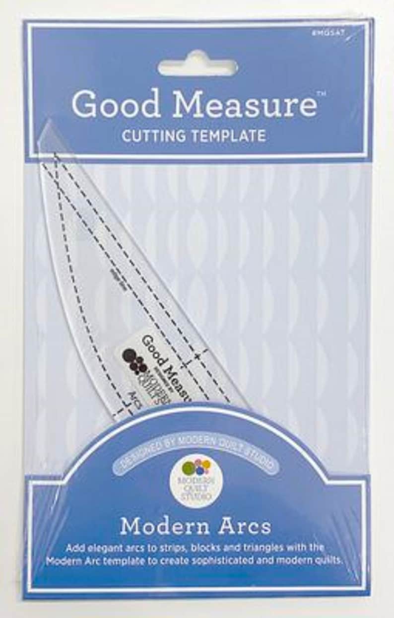 May include: A clear plastic Good Measure cutting template for quilting, packaged in a blue and white card. The template is curved with dashed lines for measurement. The package reads "Modern Arcs".