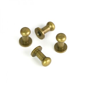 May include: Four antique brass round-headed furniture tacks with a flat base.