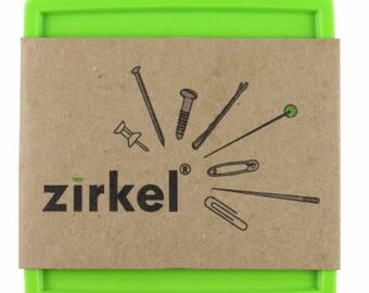 May include: A green rectangular container with a brown paper band featuring the word "zirkel" and illustrations of various fasteners, including a nail, screw, pin, and paperclip. The container is designed to hold small items.