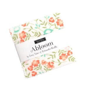 May include: A white fabric square with a floral pattern in shades of green, orange, and blue. The fabric has the text "Abloom by Corey Yoder of Coriander Quilts" printed on it.