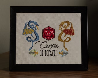 May include: A framed cross-stitch design featuring two dragons flanking a red twenty-sided die. The text "Carpe Diem" is stitched below the die.
