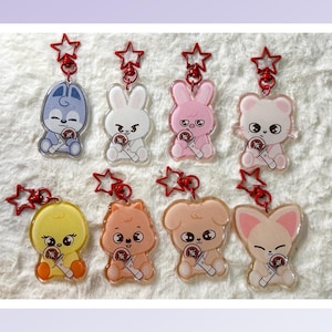 May include: A collection of eight acrylic keychains featuring cartoon animal characters. Each keychain has a red star-shaped clasp and a small microphone. The characters include a blue dog, white rabbit, pink rabbit, white bear, yellow chick, orange hamster, tan dog, and pink fox.