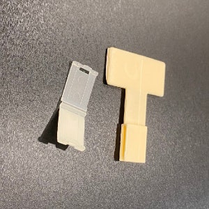 Puede incluir: Dos piezas de pl&aacute;stico, una es una pieza rectangular transparente con una parte superior curva y la otra es una pieza en forma de T beige.