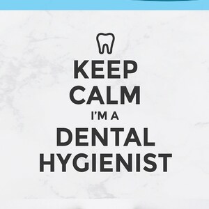 Op de afbeelding: Een wit T-shirt met een zwarte afbeelding waarop staat "Keep Calm I'm a Dental Hygienist" met een tandenpictogram boven de tekst. De afbeelding staat op een wit T-shirt. Het T-shirt ligt op een wit oppervlak.