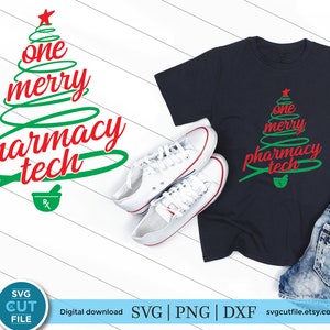 May include: A green Christmas tree design with the text "one merry pharmacy tech" in red. A mortar and pestle symbol is at the bottom of the tree. The design is on a dark blue t-shirt.