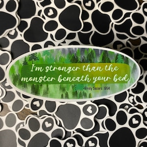 May include: A green and white oval sticker with the text "I'm stronger than the monster beneath your bed -Emily Sailers 1994". The sticker is surrounded by black and white paw print stickers.
