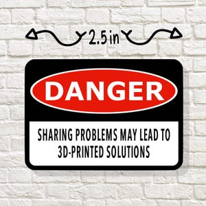 May include: A rectangular sticker with a black border and a red oval that reads "DANGER". Below, the text reads "SHARING PROBLEMS MAY LEAD TO 3D-PRINTED SOLUTIONS". The sticker is 2.5 inches wide.