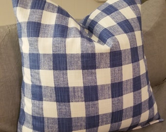 May include: A square cushion featuring a blue and white gingham design. The cushion is made of fabric and is placed on a grey surface. The cushion has a traditional farmhouse aesthetic.