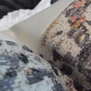 May include: Two white throw pillows with a gray and brown geometric pattern. The pillows are made of a soft, textured fabric.