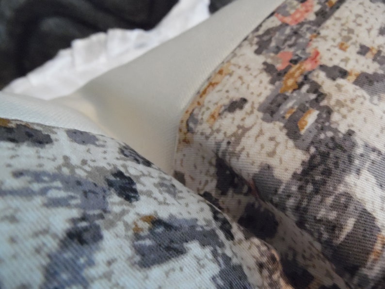 May include: Two white throw pillows with a gray and brown geometric pattern. The pillows are made of a soft, textured fabric.