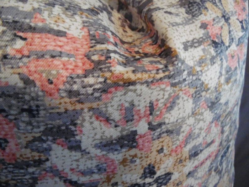 May include: Close-up of a fabric with a patterned design featuring shades of pink, gray, and beige. The fabric has a textured surface and a slightly wrinkled appearance.