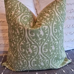 May include: A green and white patterned throw pillow with a damask design. The pillow is made of a soft, textured fabric.