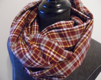 Könnte beinhalten: Burgunderfarbener, gelb- und weiß karierter Loop-Schal. Der Schal ist aus weichem Stoff gefertigt und um einen schwarzen Schaufensterpuppenkopf gewickelt. Ein gemütliches Accessoire für kühleres Wetter.