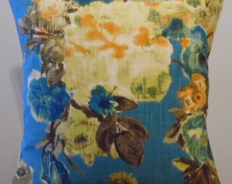 May include: A blue throw pillow with a floral pattern featuring large white, orange, and blue flowers. The background is a light blue with a subtle texture.
