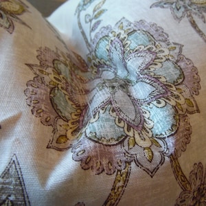 May include: A white fabric with a floral pattern in shades of brown, purple, and blue. The fabric has a textured surface and a paisley design.
