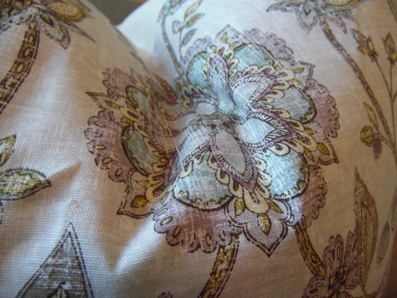 May include: A white fabric with a floral pattern in shades of brown, purple, and blue. The fabric has a textured surface and a paisley design.