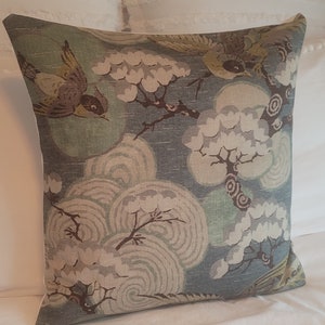 May include: A decorative throw pillow with a blue background and a pattern of stylized birds, flowers, and swirling clouds in shades of brown, green, and white.